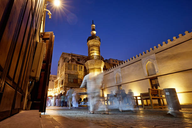 Pedestrians walking through historic Jeddah at twilight