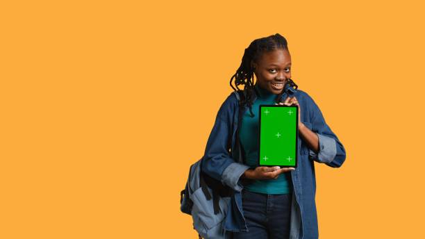 istock Smiling woman presenting tablet with green screen display, studio background 2168072141