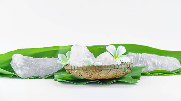 istock Clear and pristine alum cubes resting in a bamboo basket alongside leaves, set against a white background. 2168073665