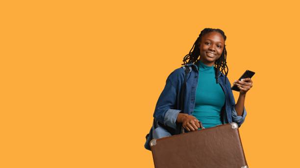 istock Smiling girl going on vacation with suitcase, reading texts, studio background 2168075487