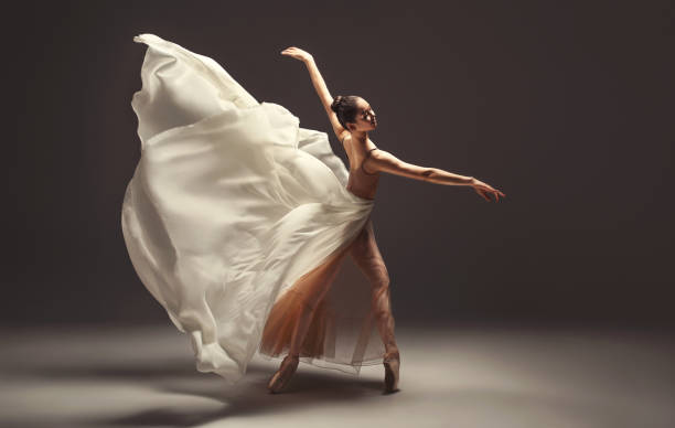 istock Graceful young woman ballet dancer is performing classical ballet.  Wings from tender silk is flying behinde her. 2168079439