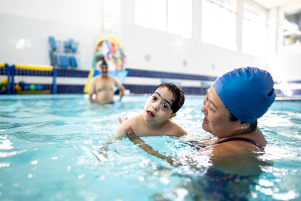 istock Instructor and boy with down syndrome on a swimming lesson 2168079957