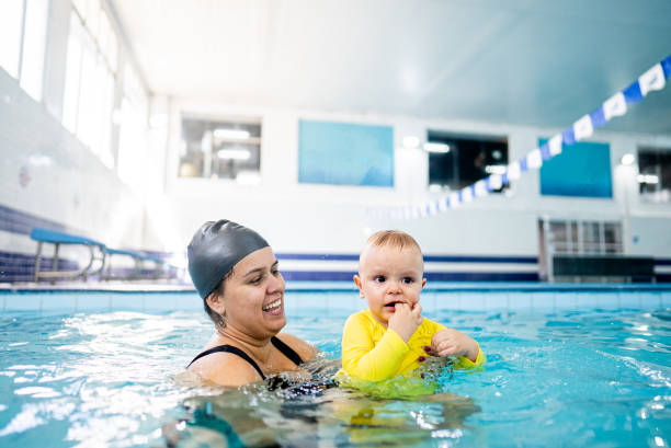 istock Instructor helping a baby boy during exercise at swimming pool 2168080084