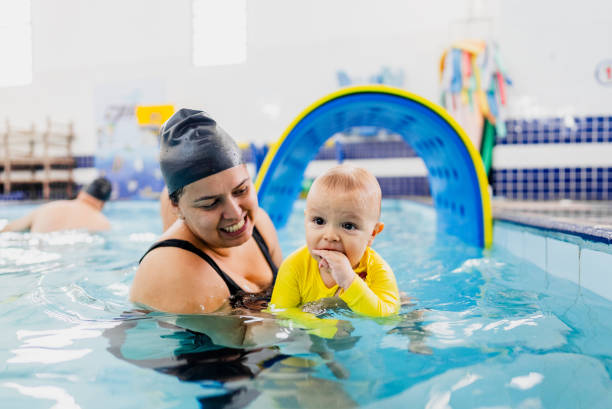 istock Mother helping a baby boy son during exercise at swimming pool 2168080220