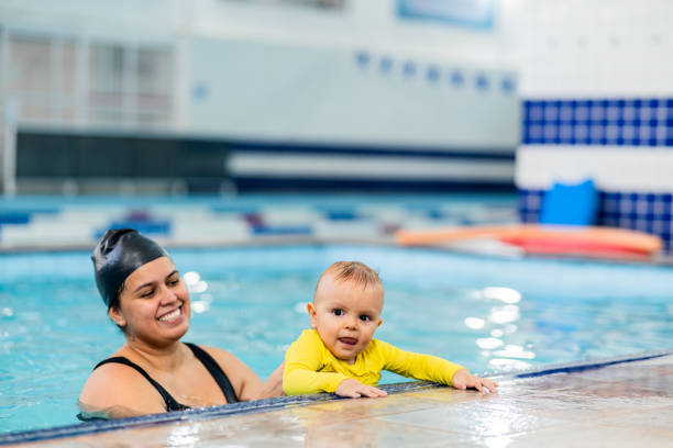 istock Mother helping a baby boy son during exercise at swimming pool 2168080250