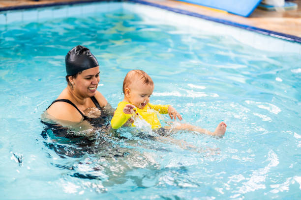 istock Mother helping a baby boy son during exercise at swimming pool 2168080258