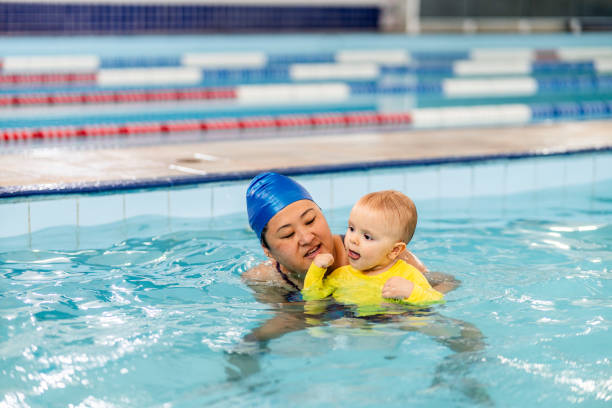 istock Instructor helping a baby boy during exercise at swimming pool 2168080285