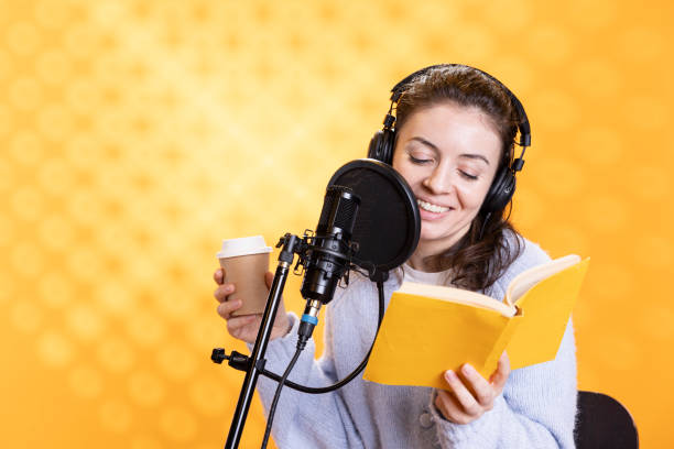 istock Smiling woman reads ebook from ereader, records audiobook using, drinks coffee 2168080538