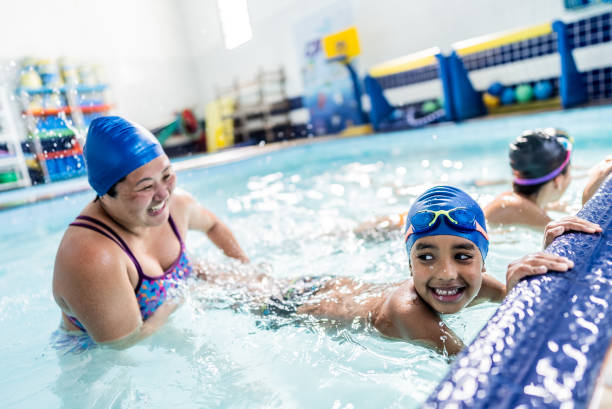istock Instructor helping a child boy at swimming pool 2168080764