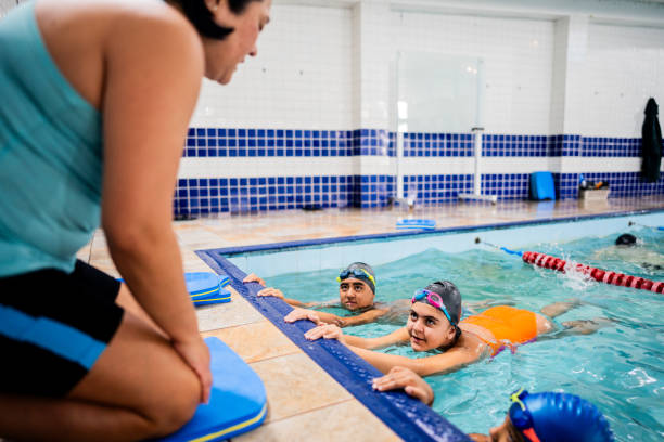 istock Instructor talking with children during exercise class at swimming pool 2168081067