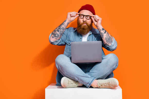 istock Photo of funky doubtful guy dressed denim jacket working modern device looking empty space isolated orange color background 2168082953