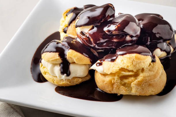 istock Profiterole. Profiteroles with Chocolate Sauce. Eclairs with cream and chocolate sauce on a plate. Delicious Profiterole cake. Profiteroles glazed with chocolate. 2168083445