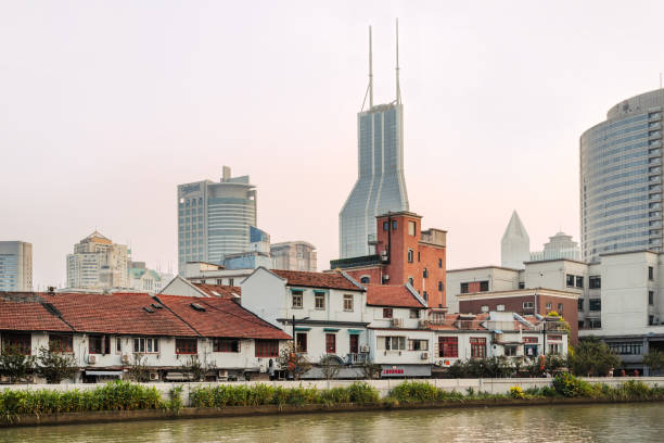 A scenic view of traditional and modern architecture blending harmoniously by the riverside in Shanghai, China, depicting urban growth and historical preservation.