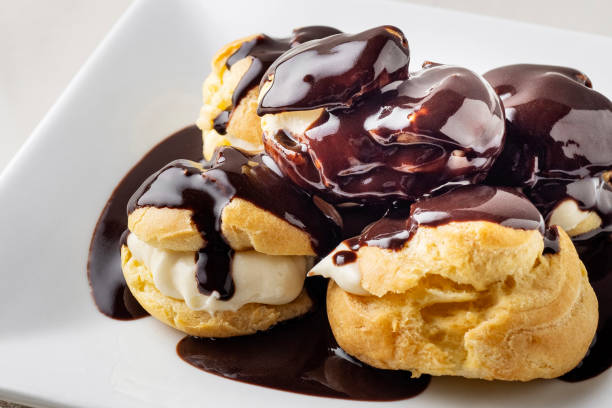 istock Profiterole. Profiteroles with Chocolate Sauce. Eclairs with cream and chocolate sauce on a plate. Delicious Profiterole cake. Profiteroles glazed with chocolate. 2168083940