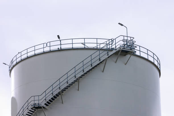 Two white storage fuel tanks in oil industrial refinery area against blue sky background, low angle view with copy space