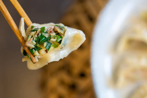 Close up of someone holding a dumpling with chopsticks