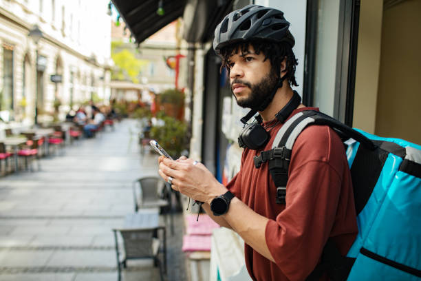 istock Young man using a phone while delivering food on a bicycle in a city 2168091995