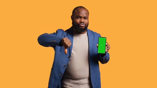 istock Man showing thumbs down sign gesturing holding green screen phone 2168092570