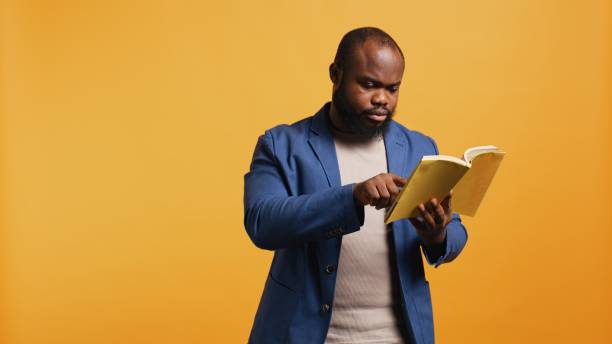 istock Man struggling to read book with small font, pointing finger to words 2168094838