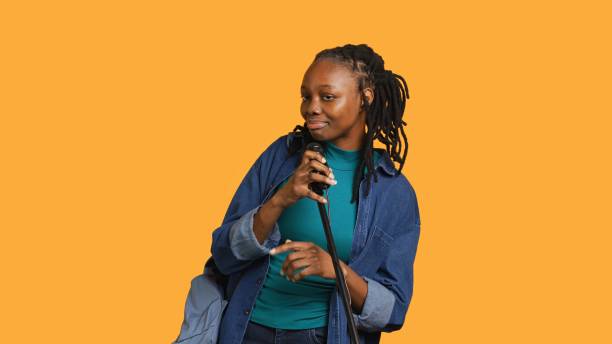 istock Woman with microphone singing and dancing, studio background 2168097650