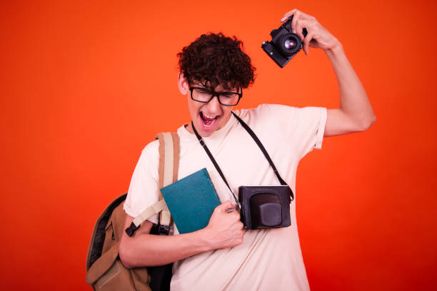 Side view shot of male university student with backpack and camera.