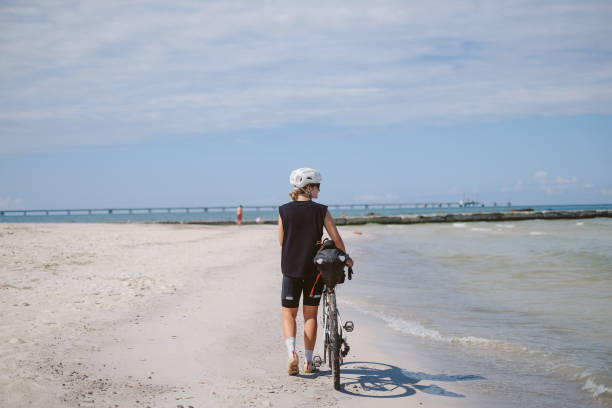 Young woman walks on beach with bicycle