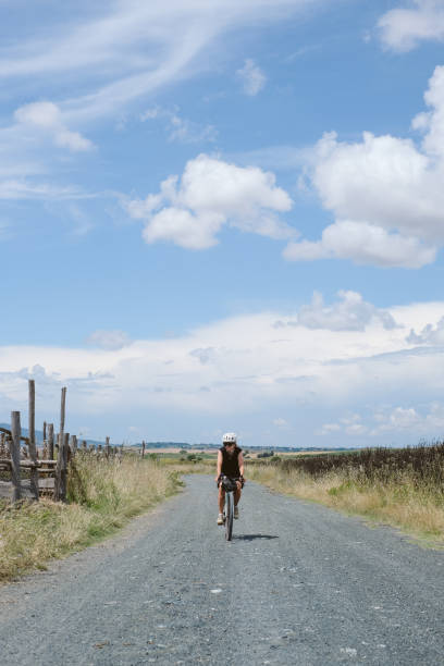 istock Young woman bicycles down rural road 2168102304
