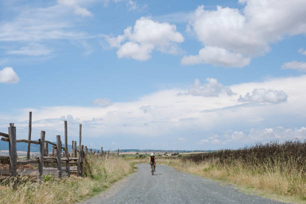 Young woman bicycles down rural road