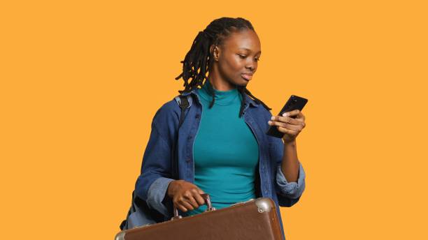 istock Smiling girl going on vacation with suitcase, reading texts, studio background 2168102406