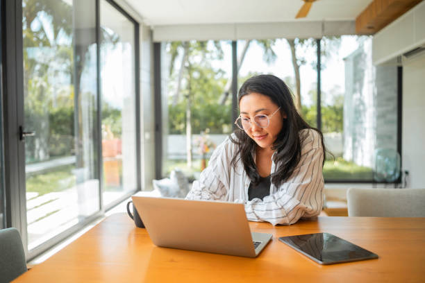 istock Smiling Asian Woman Working Remotely with Coffee 2168105227