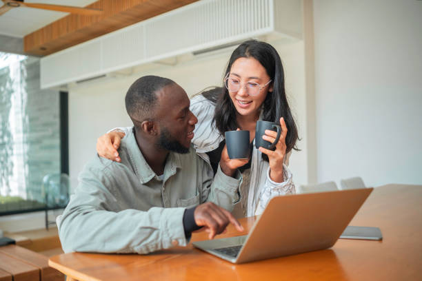 istock Asian Woman and Black Man Collaborate with Tech at Home 2168105248