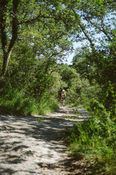 istock Young woman rides rural road through forest, Tuscany 2168106900