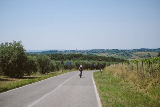 istock Young woman bicycles through agricultural fields, Tuscany 2168106930