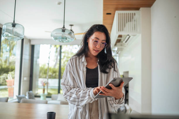 istock Cheerful Asian Woman with Tablet in Home Interior 2168106987