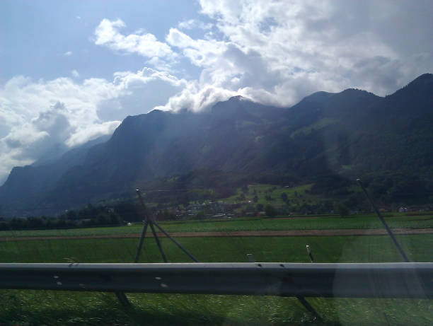 View of the mountains over the curb under the sky with clouds from a passing car