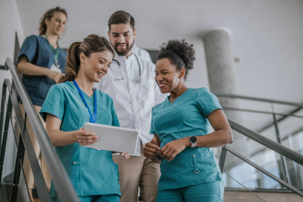 istock Three medical professionals discuss patient information on a tablet while walking downstairs in a hospital 2168117218