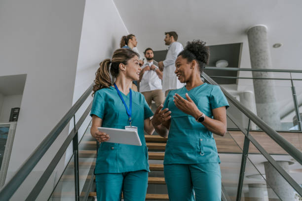 istock Two female doctors chatting while walking upstairs in a hospital 2168117543