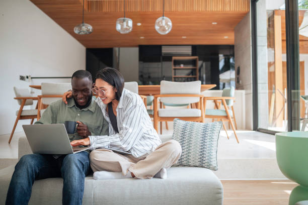 istock Joyful Diverse Couple Using Technology on Living Room Sofa 2168120285