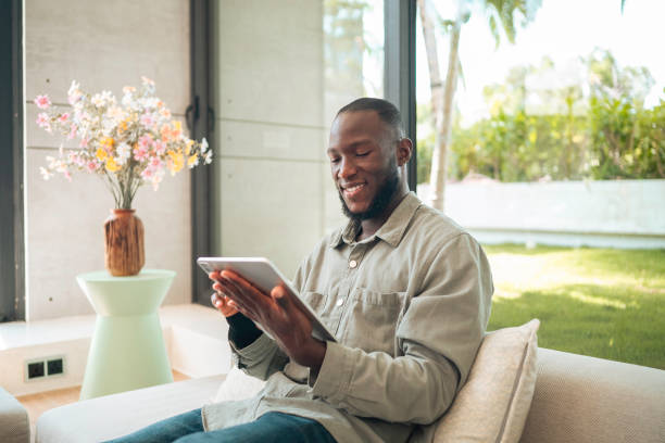 istock Smiling Black Man Enjoying Tablet Time on Living Room Couch 2168120295