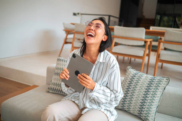 istock Joyful Asian Woman with Tablet on Couch 2168120313