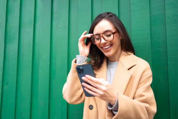istock Close up smiling woman using smartphone, standing near Christmas tree 2168120949