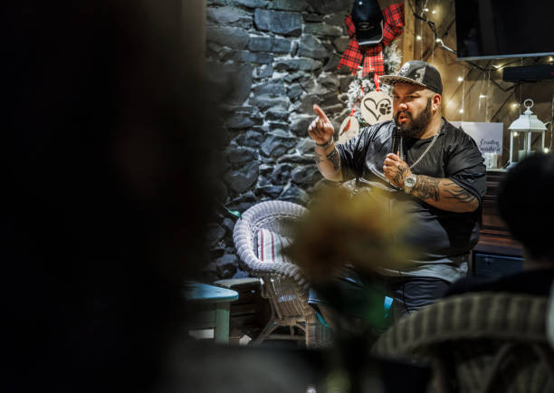 istock Entertaining crowd with comedic flair. Plus-size bearded Latino comic performs at rustic club. Looking from the crowd 2168136350