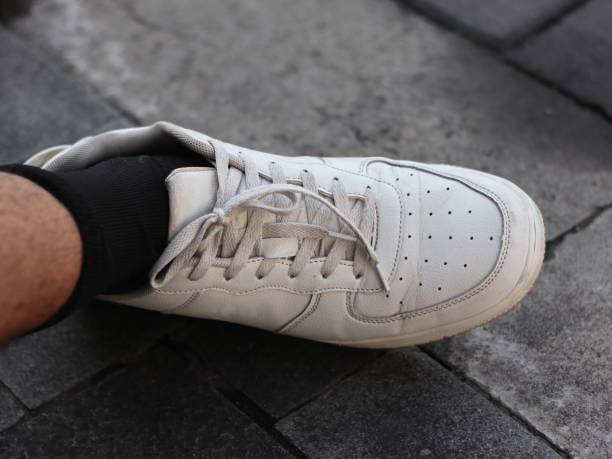 Man's feet wearing white sneakers and black socks