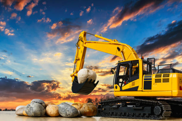Excavator  concept  with a stone lap in  bucket  lift up on on sunset sky background