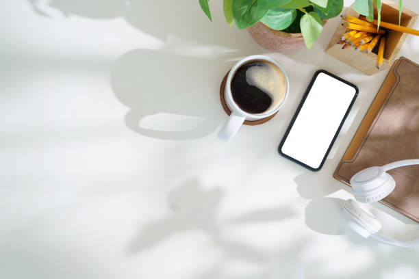 istock Modern workplace with smart phone, notebook and coffee cup on white table. Top view with copy space. 2168149716