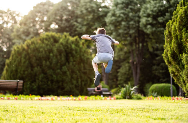 rear view happy boy jumping in the park at spring