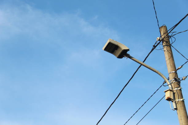 Electric poles and streetlights lit up on a sunny morning