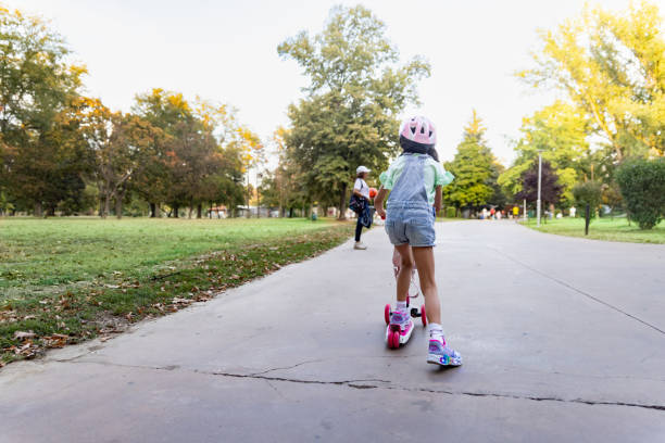 Filipino family in a city park. Weekend activities with the children, driving push scooters.