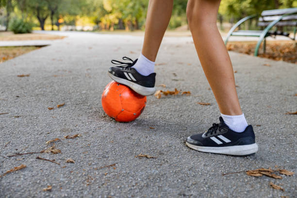 Close up of a 11 year old boy playing with football in a public park