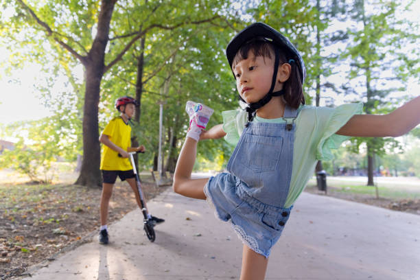 Filipino brother and sister having fun at the park. Weekend activities, driving push scooters.